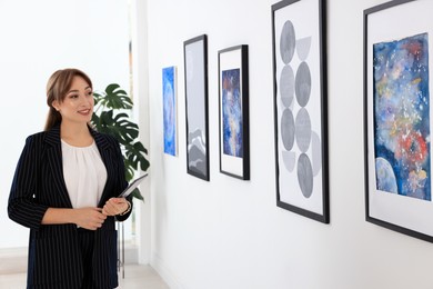 Beautiful young woman with tablet at exhibition in art gallery