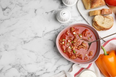 Bowl of delicious stuffed pepper soup served on white marble table, flat lay. Space for text