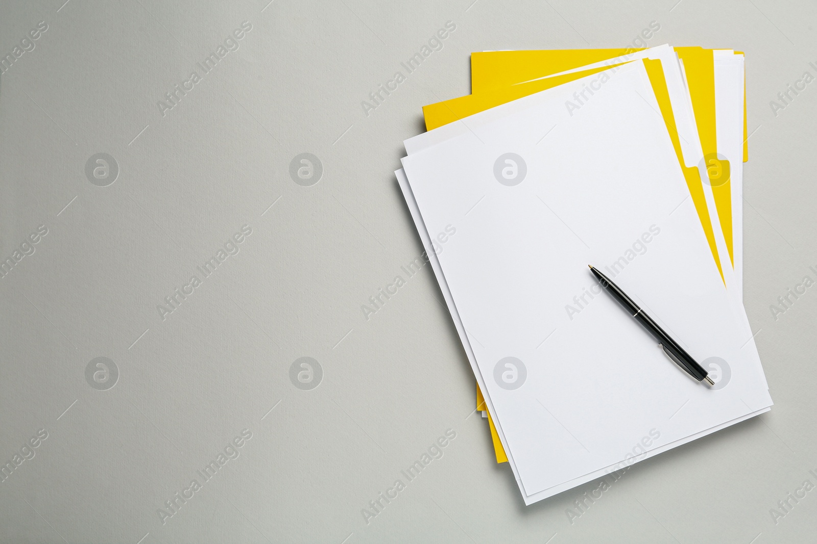 Photo of Yellow files with blank sheets of paper and pen on light grey background, top view. Space for text