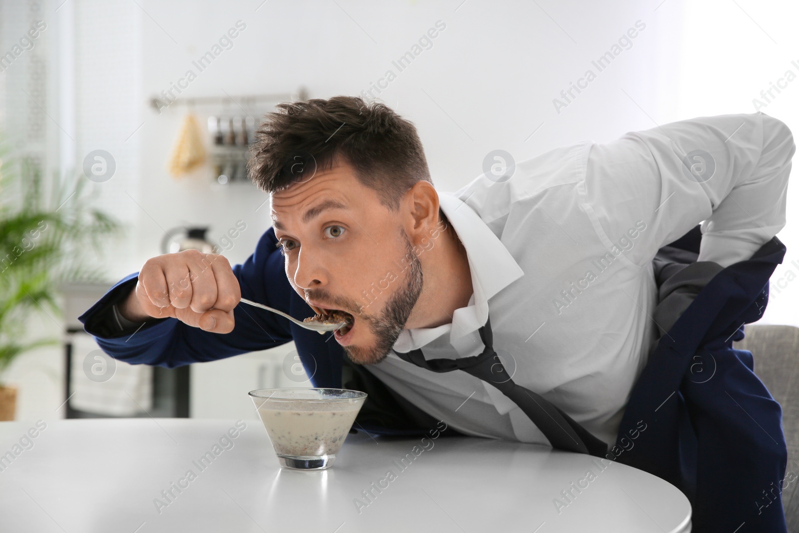 Photo of Man eating breakfast in hurry at home. Morning preparations