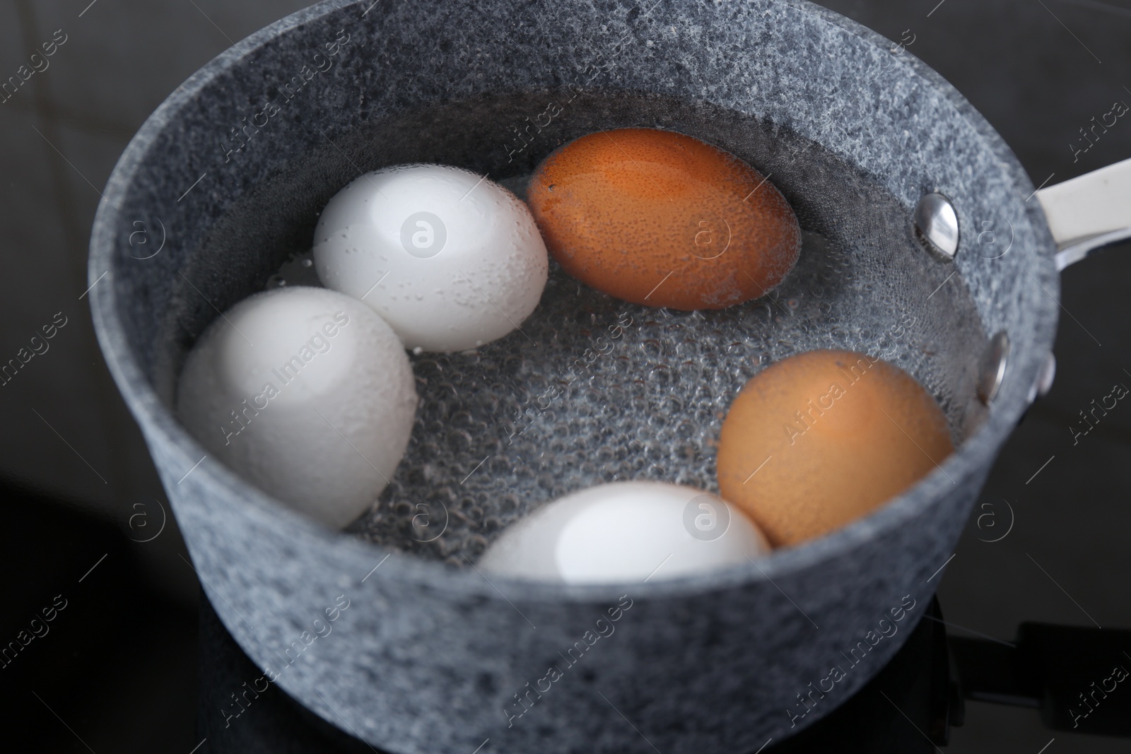 Photo of Chicken eggs boiling in saucepan on electric stove, closeup
