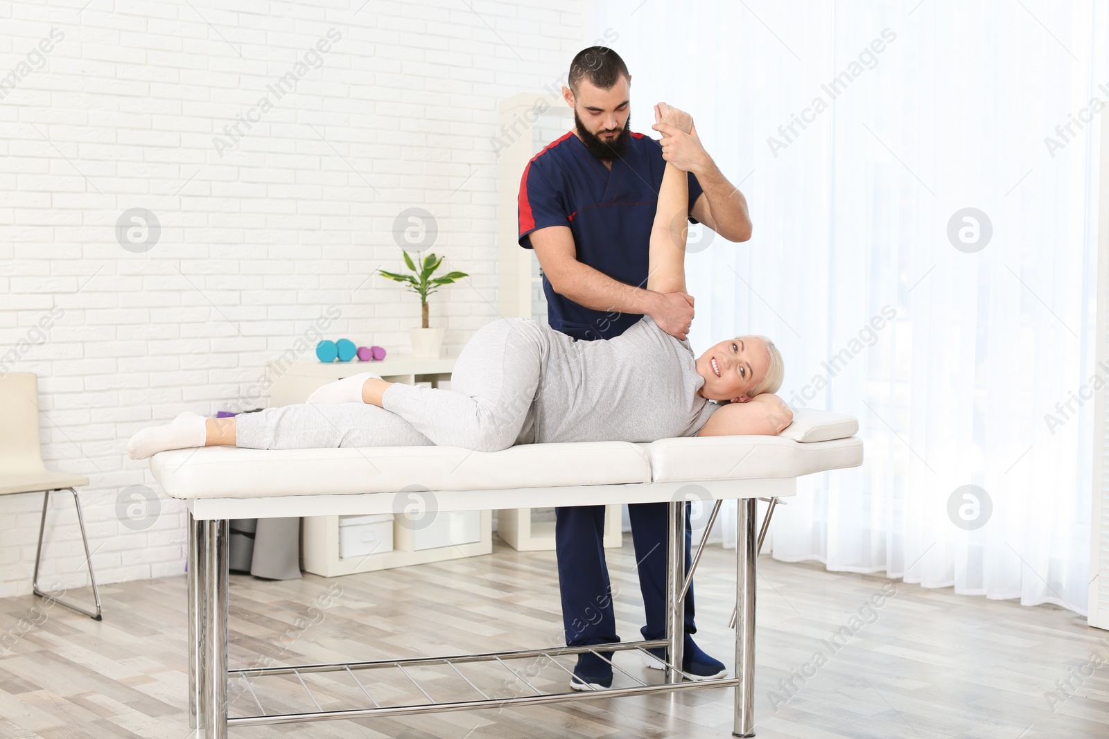 Photo of Physiotherapist working with patient in clinic. Rehabilitation therapy