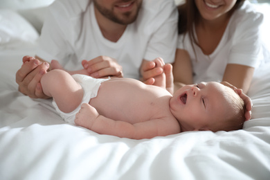 Photo of Happy couple with their newborn baby on bed, closeup