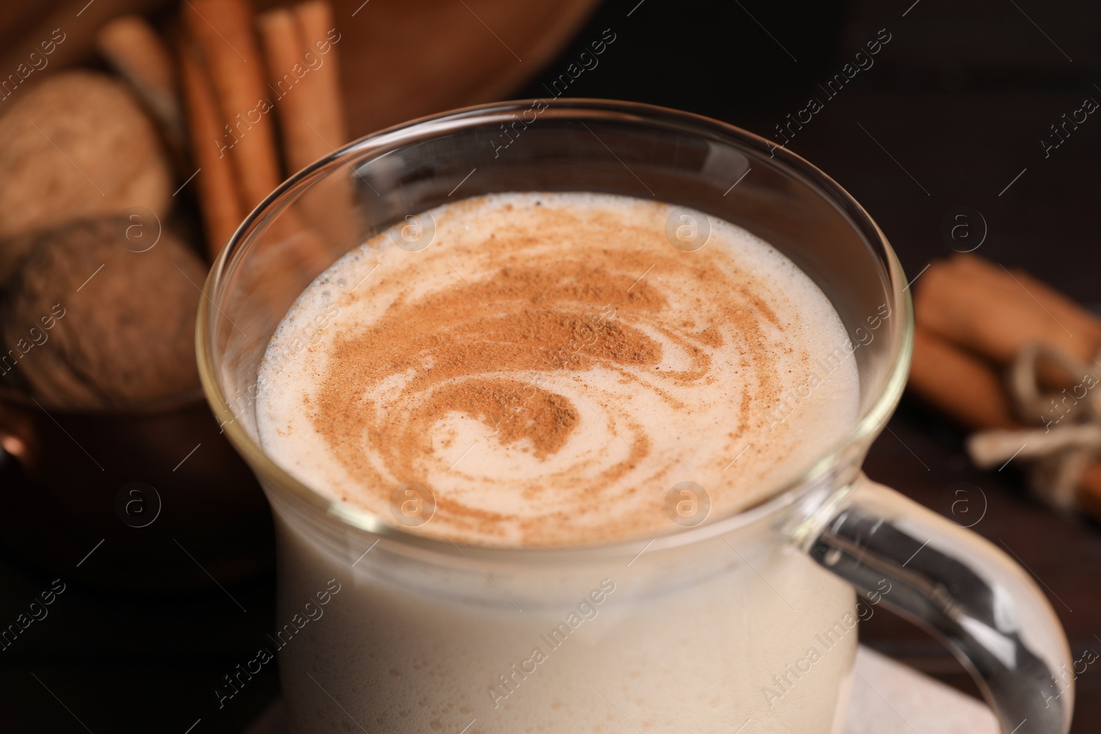 Photo of Glass cup of delicious eggnog on wooden table, closeup