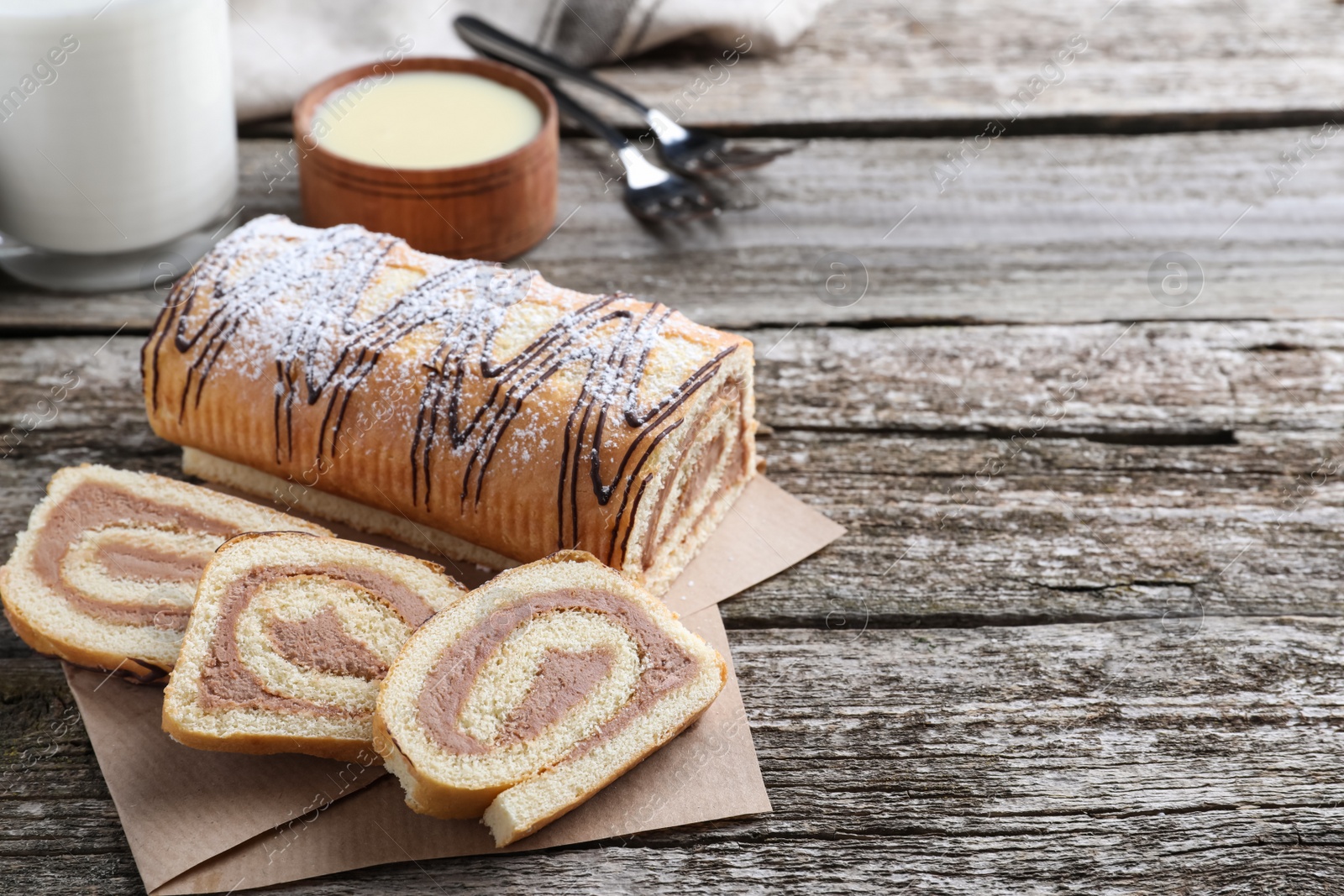 Photo of Tasty cake roll with cream on wooden table, space for text