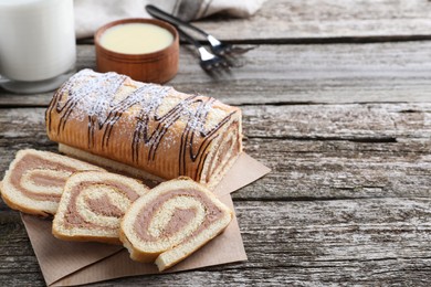 Photo of Tasty cake roll with cream on wooden table, space for text