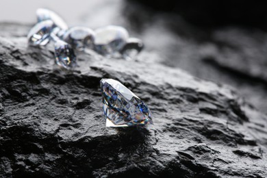 Photo of Different shiny diamonds on wet stone surface. Space for text
