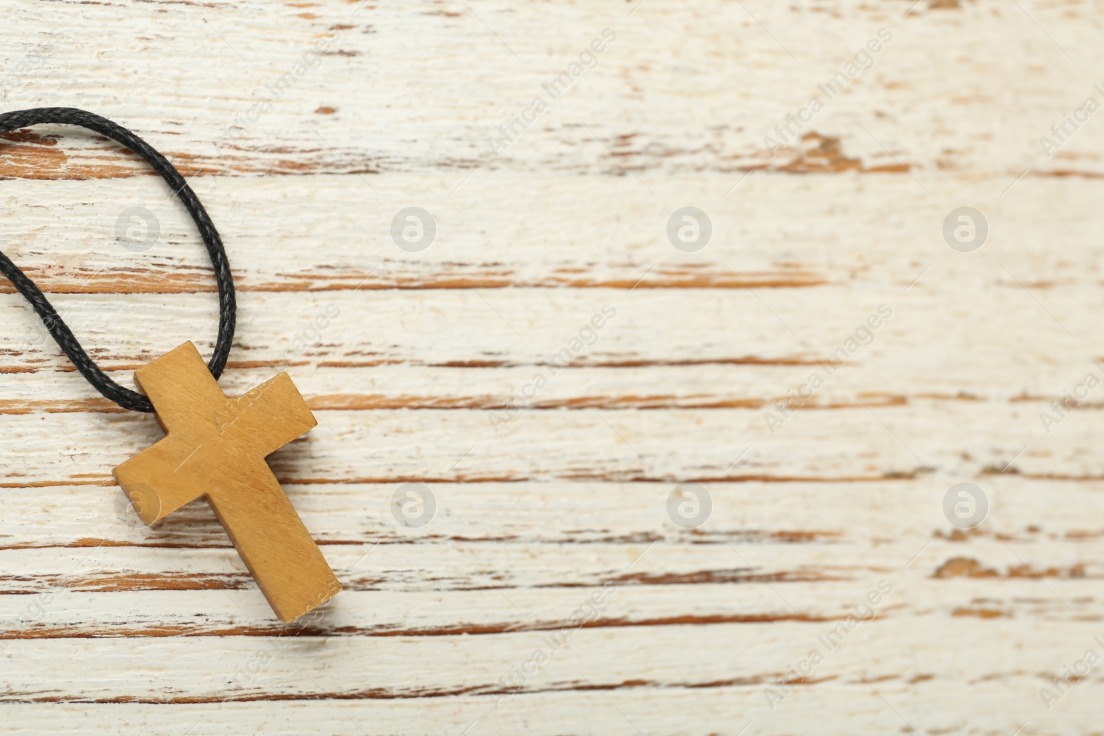 Photo of Christian cross on white wooden table, top view. Space for text