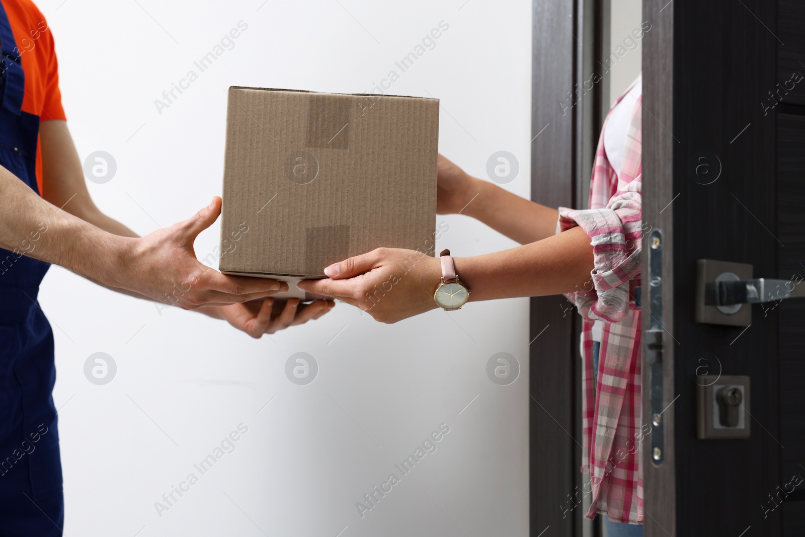 Photo of Woman receiving parcel from courier at home, closeup