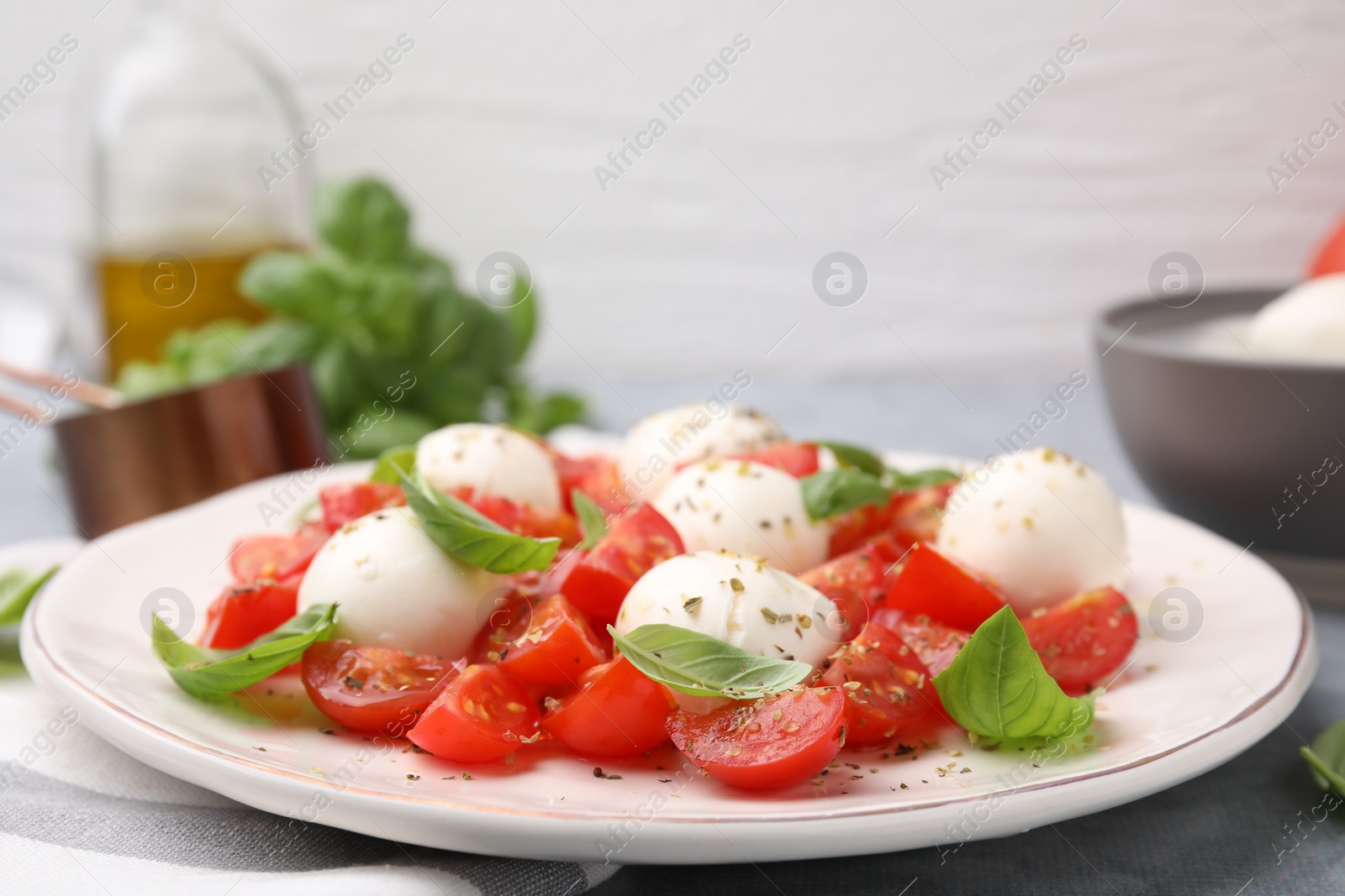 Photo of Tasty salad Caprese with tomatoes, mozzarella balls and basil on table, closeup. Space for text