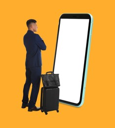 Businessman with travel bags standing in front of big smartphone on orange background