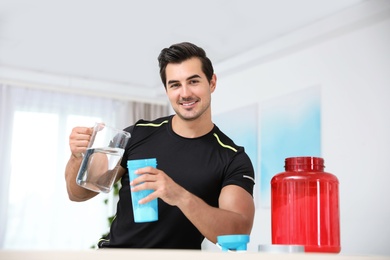 Photo of Young athletic man preparing protein shake at home