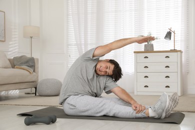 Photo of Overweight man stretching on mat at home