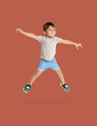 Happy boy jumping on brown background, full length portrait