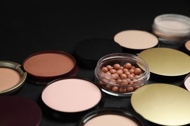 Photo of Different face powders on black background, closeup