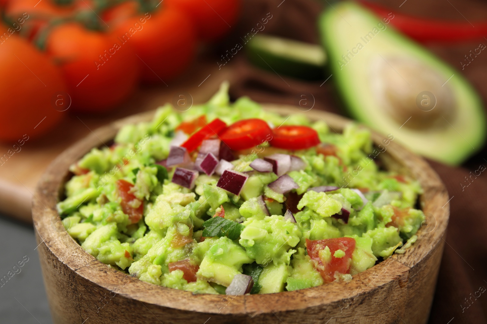 Photo of Delicious guacamole in wooden bowl, closeup view