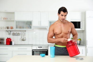 Young shirtless athletic man preparing protein shake in kitchen, space for text