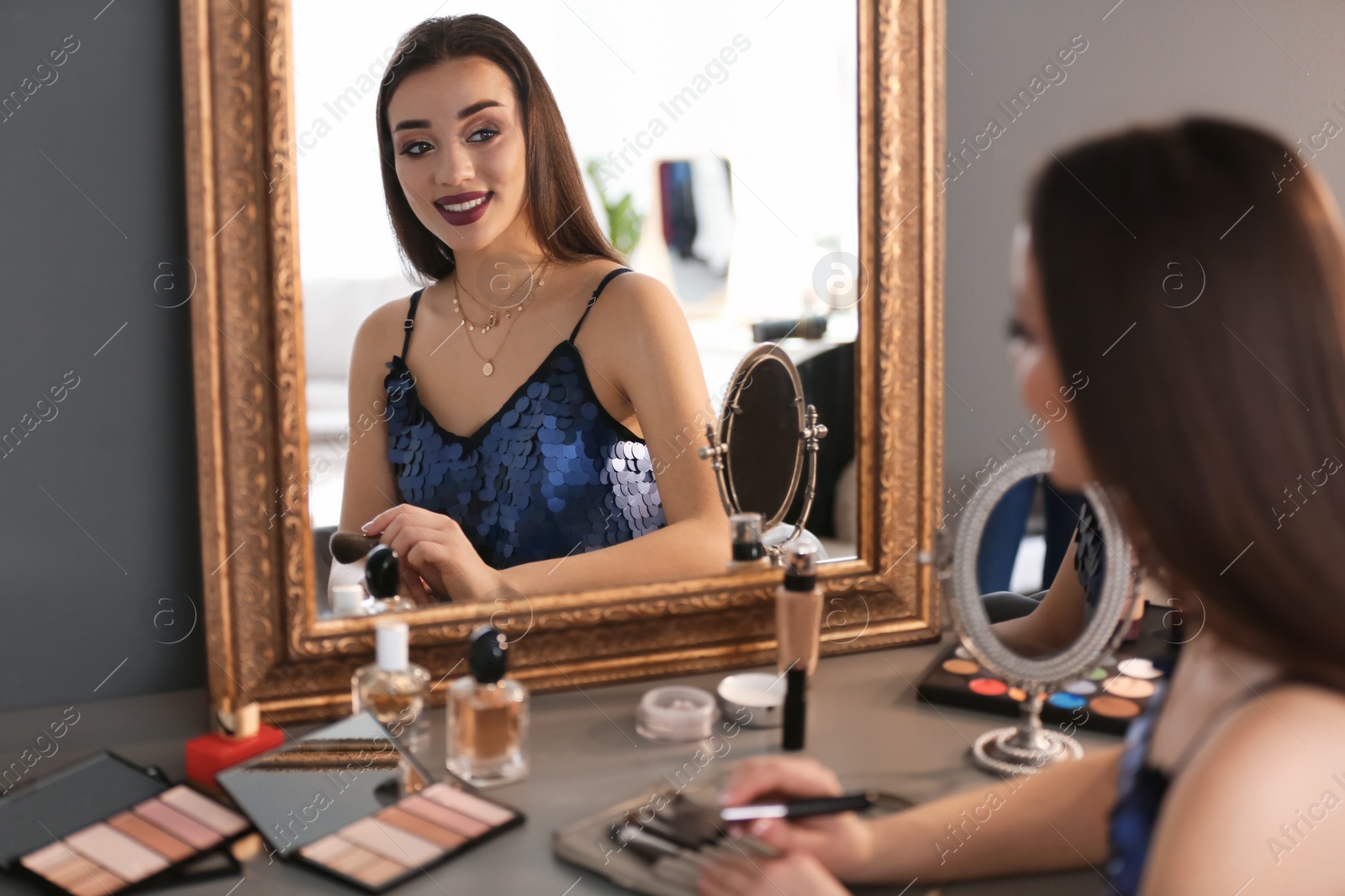 Photo of Portrait of beautiful woman with bright makeup near mirror indoors