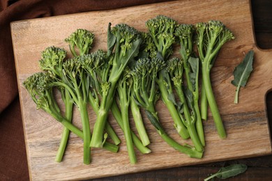 Photo of Fresh raw broccolini on wooden board, top view. Healthy food