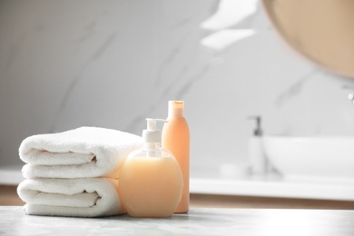 Photo of Folded towels and toiletries on marble table in bathroom, space for text