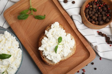 Photo of Bread with cottage cheese and basil on grey table, flat lay