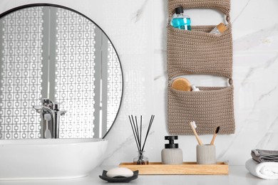 Photo of Knitted organizer hanging on wall in bathroom