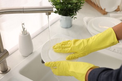 Photo of Woman washing plate at sink in kitchen, closeup