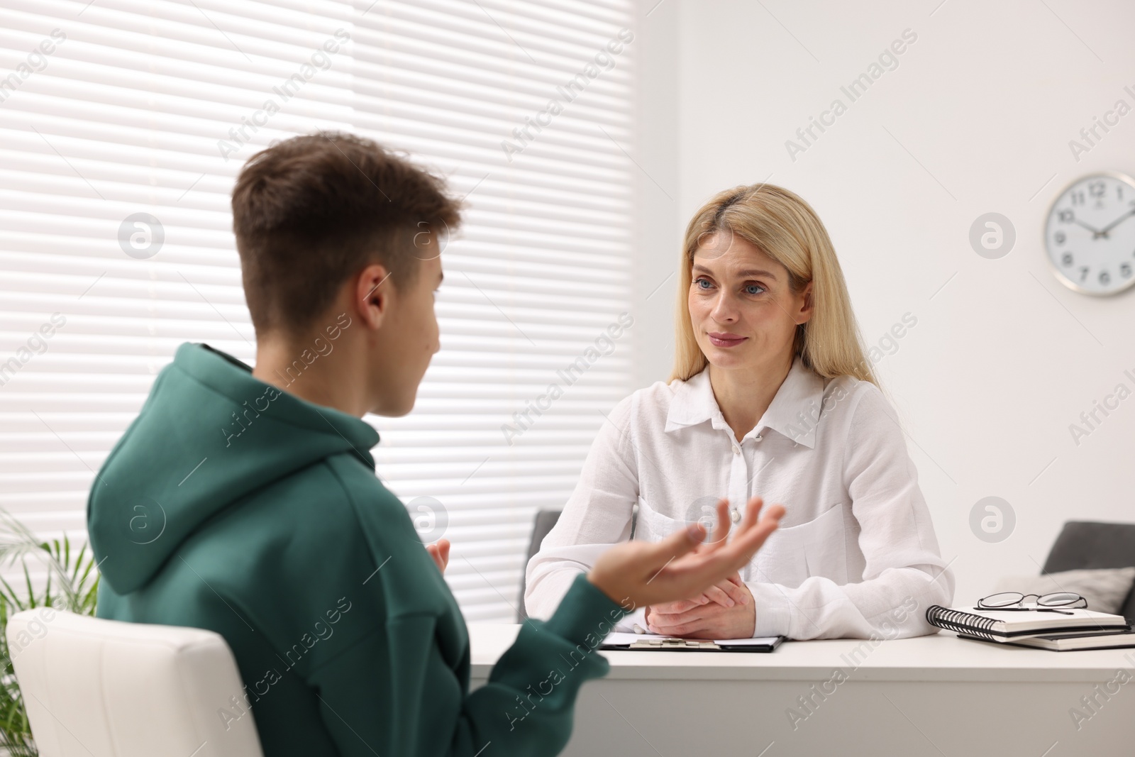 Photo of Psychologist working with teenage boy at table in office