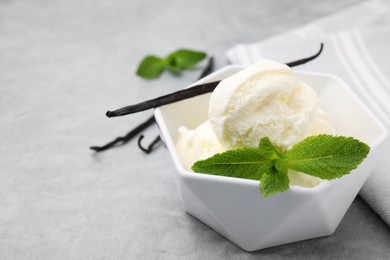 Photo of Delicious ice cream, mint and vanilla pod on light grey table, closeup. Space for text