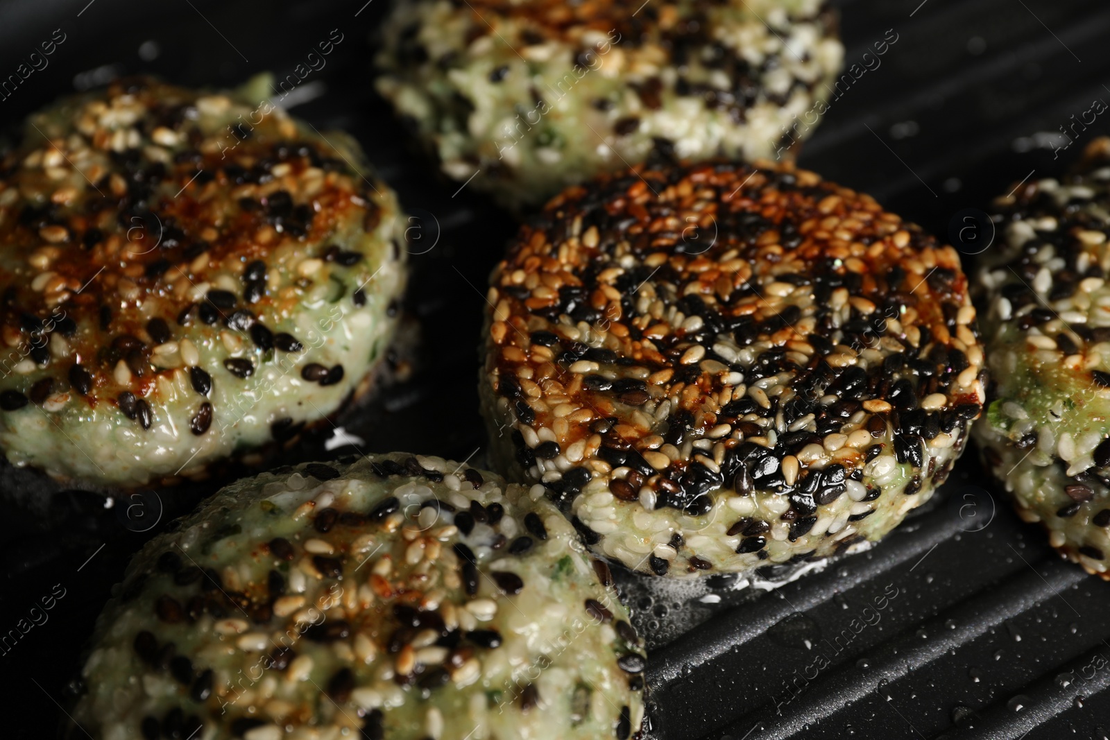 Photo of Cooking tasty vegan cutlets with sesame in grill pan, closeup