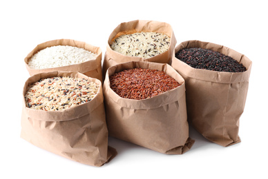 Photo of Brown and polished rice in paper bags on white background