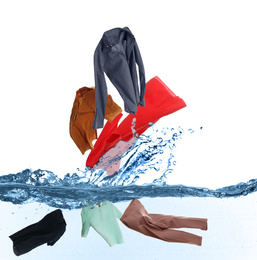 Different clothes falling into water against white background