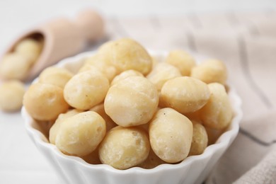 Photo of Tasty peeled Macadamia nuts in bowl on table, closeup