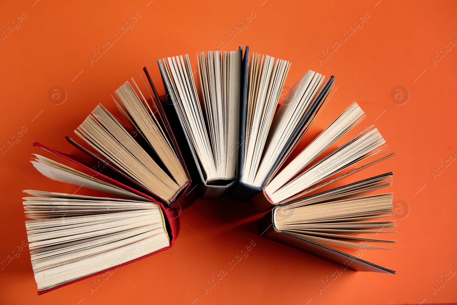 Photo of Hardcover books on orange background, flat lay