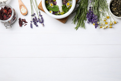 Photo of Flat lay composition with healing herbs on white wooden table. Space for text