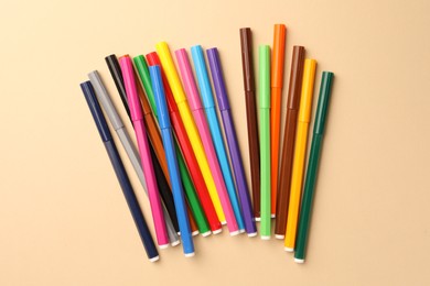 Many bright markers on beige background, flat lay