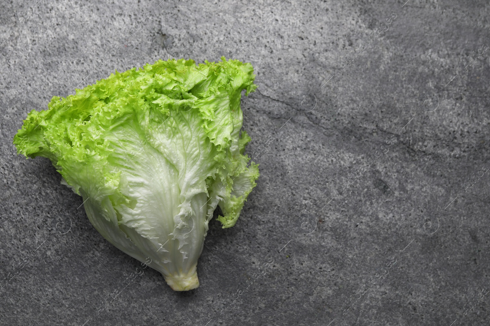 Photo of Fresh lettuce on stone table, top view and space for text