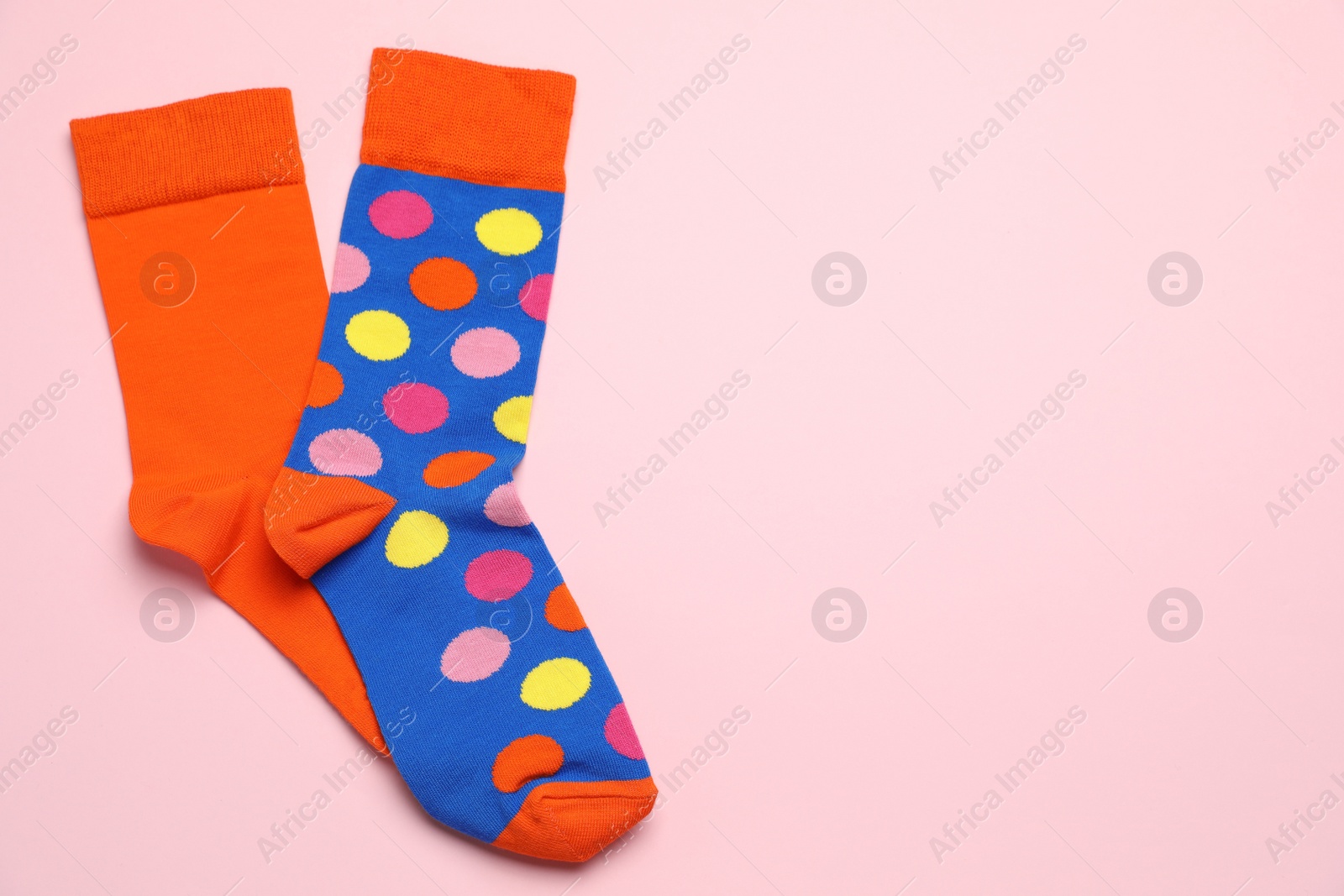 Photo of Colorful socks on light pink background, flat lay. Space for text