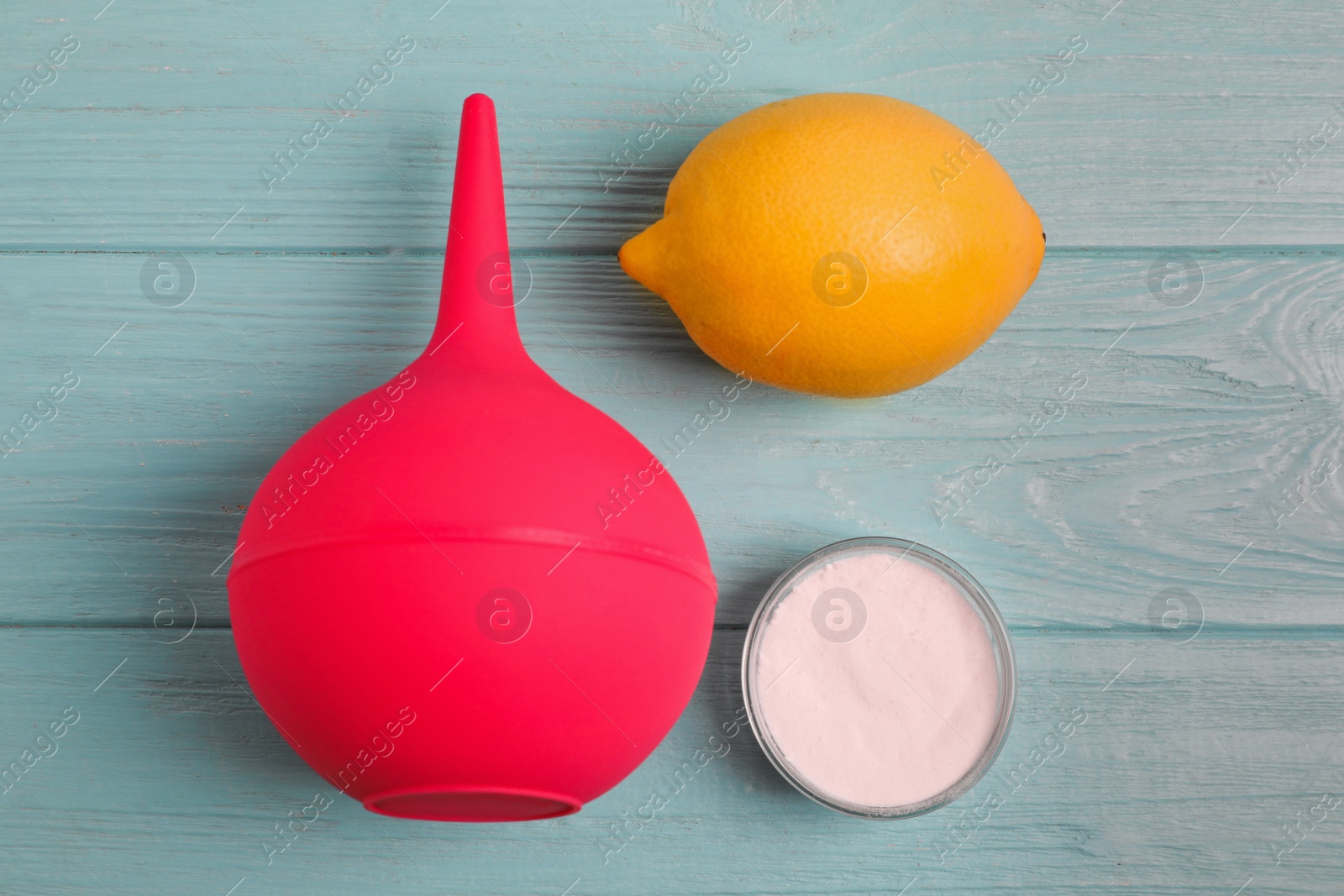 Photo of Enema, lemon and bowl of salt on green wooden table, flat lay. Medical treatment