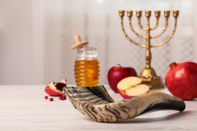 Photo of Shofar and other Rosh Hashanah holiday attributes on white wooden table indoors