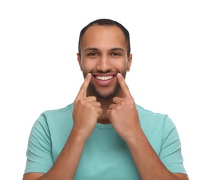 Photo of Smiling man pointing at his healthy clean teeth on white background