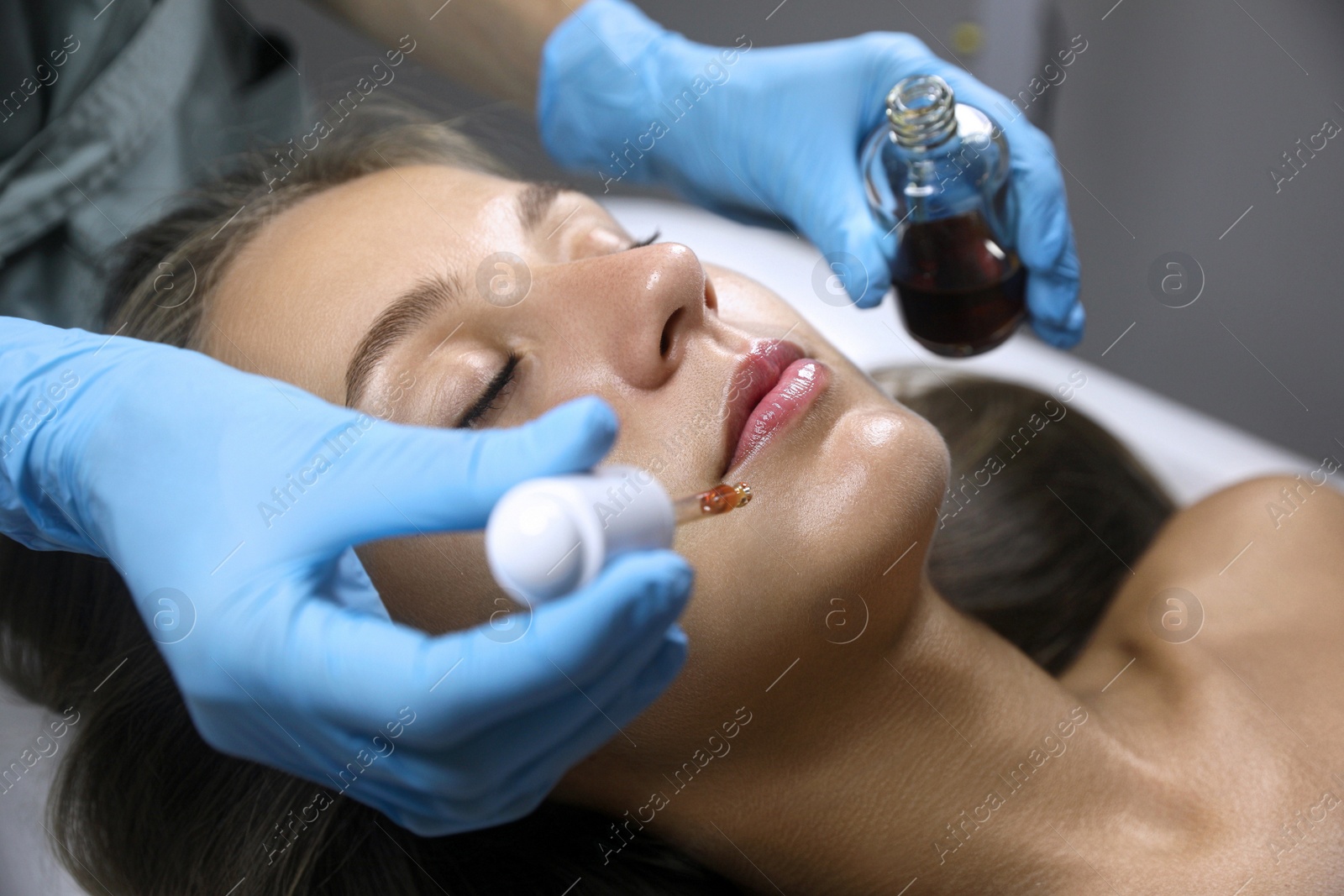 Photo of Cosmetologist applying serum on client's face in salon