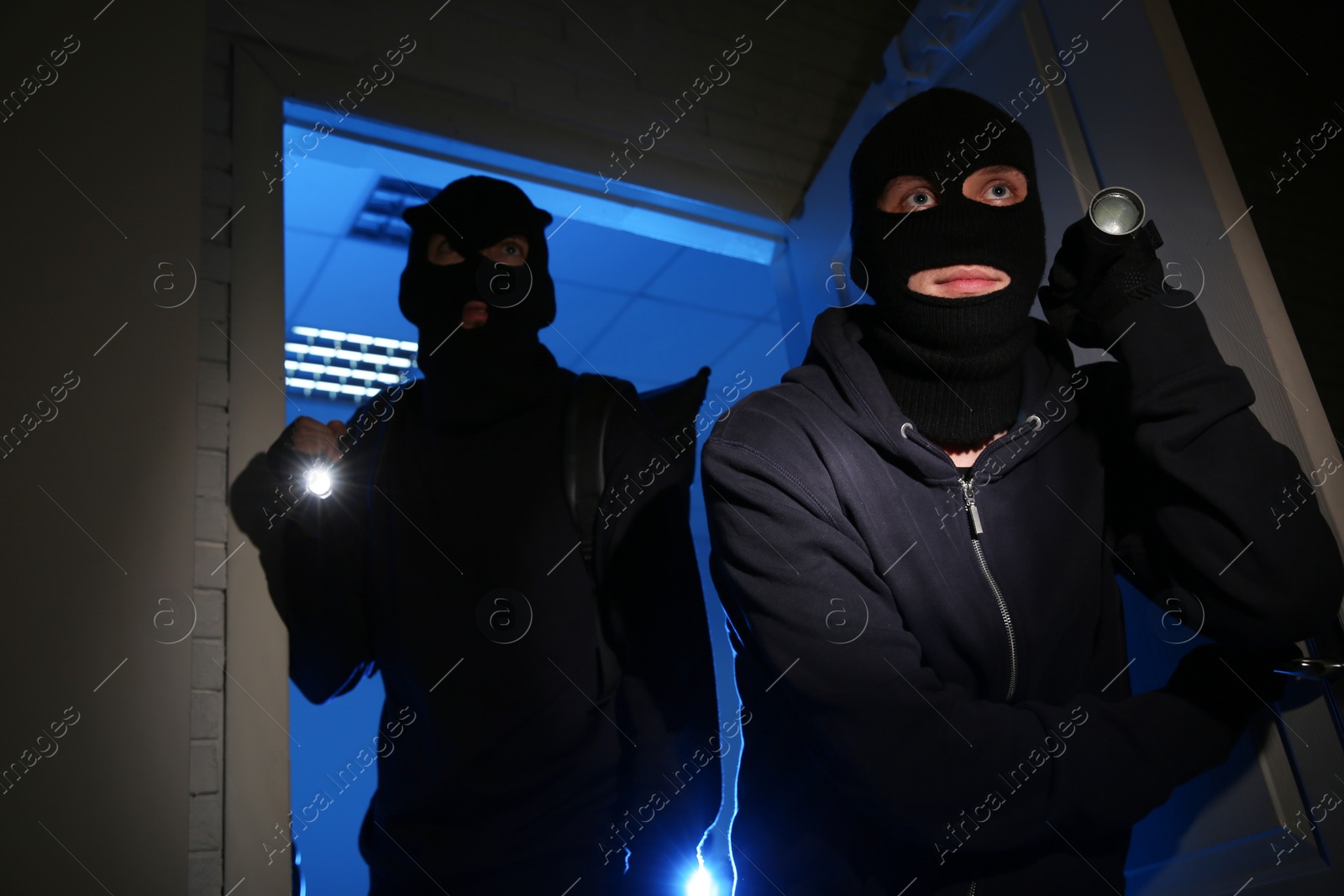 Photo of Thieves with flashlights breaking into house at night