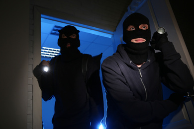 Photo of Thieves with flashlights breaking into house at night