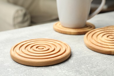 Stylish wooden cup coasters on light grey table