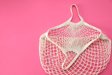 White string bag on bright pink background, top view. Space for text