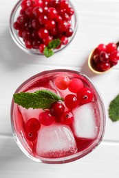 Photo of Tasty cranberry juice with ice cubes in glass and fresh berries on white wooden table, flat lay