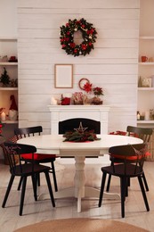 Photo of Cozy dining room interior with beautiful Christmas wreath and fireplace