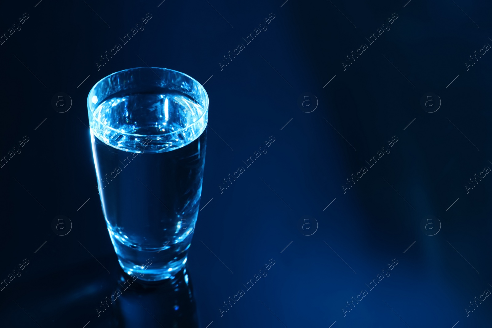 Photo of Glass of vodka on dark table, space for text