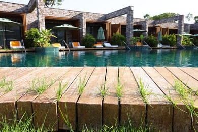 Wooden deck with grass, swimming pool and recreational area at luxury resort
